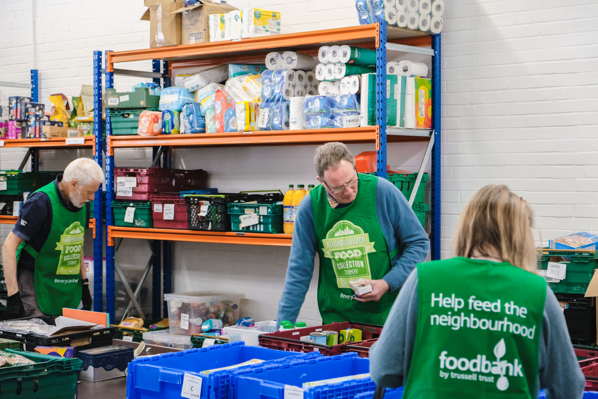 Three volunteers packing crates in the foodbank warehouse