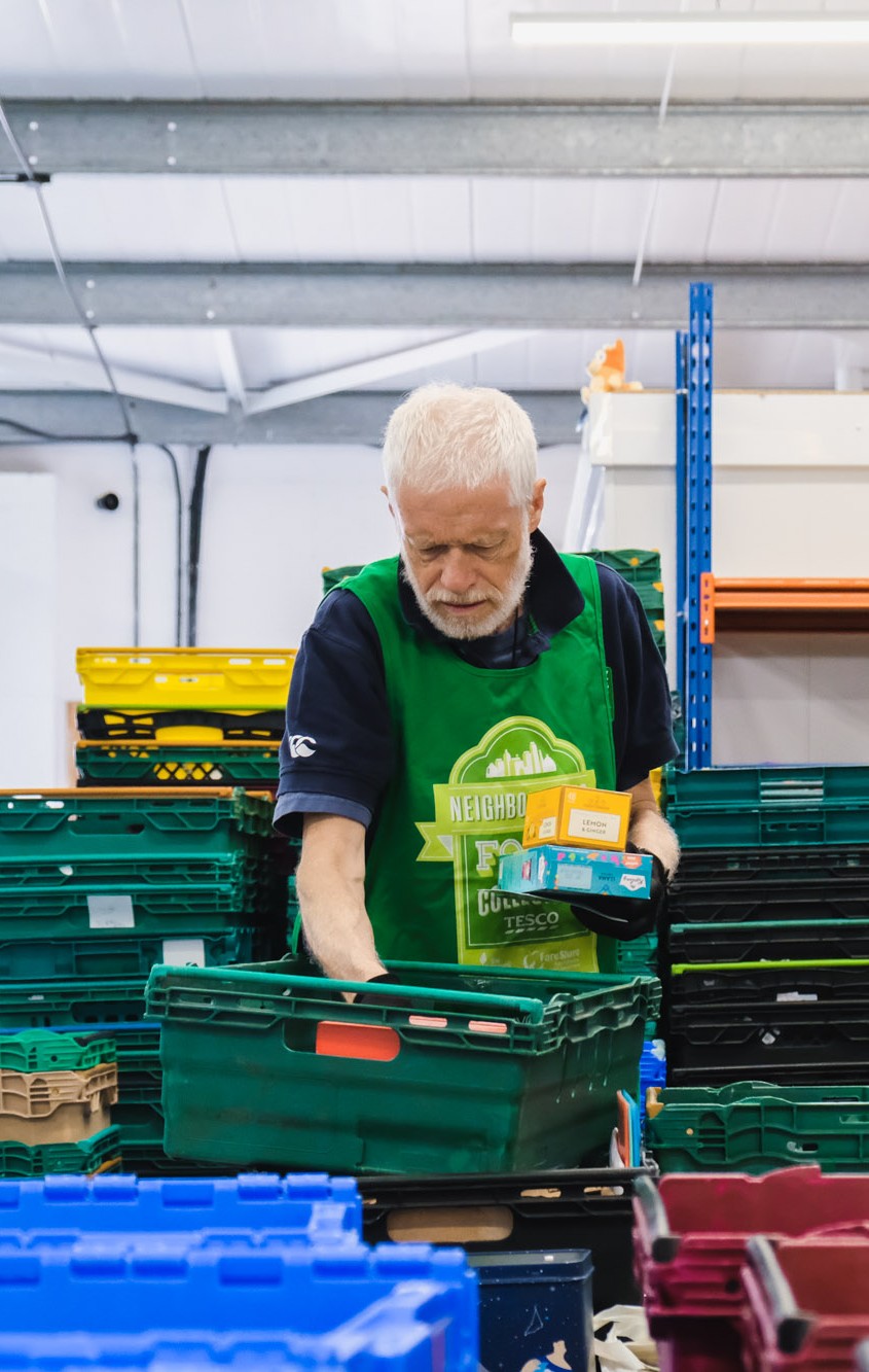 A volunteer packs a crate in the foodbank warehouse